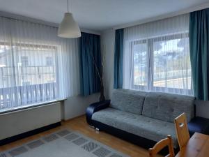 バードガシュタインにあるApartment Landhaus St- Georg-1 by Interhomeのソファと2つの窓があるリビングルーム