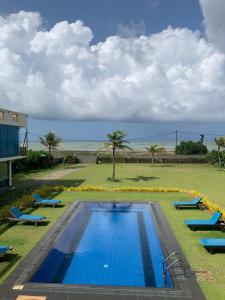 a large swimming pool with blue chairs and the beach at Calypso Sunset in Iranawila