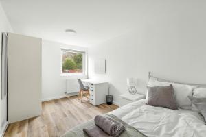 ein weißes Schlafzimmer mit einem Bett und einem Schreibtisch in der Unterkunft 20% Off Spacious Stylish Home with Free Parking in Exeter