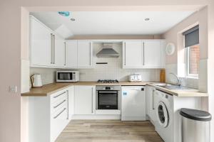 una cucina bianca con armadietti e elettrodomestici bianchi di 20% Off Spacious Stylish Home with Free Parking a Exeter