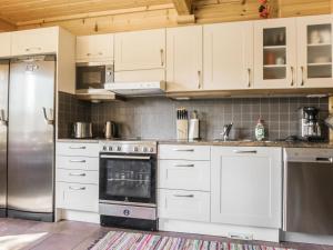 cocina con armarios blancos y nevera de acero inoxidable en Holiday Home Koparanperä by Interhome en Kakslauttanen
