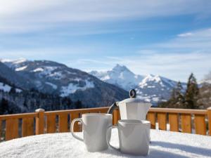 two coffee mugs sitting on a table in the snow at Chalet Chalet les Pars by Interhome in Gryon