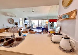 a kitchen with a sink and a living room at The Salty Seagull – ocean-view luxe! in Encounter Bay