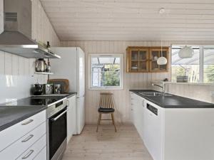 eine Küche mit weißen Schränken und schwarzen Arbeitsplatten in der Unterkunft Holiday Home Thorid - 850m from the sea in Sealand by Interhome in Fårevejle