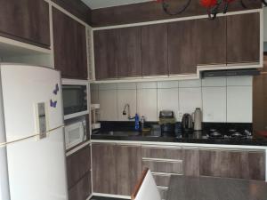 a kitchen with wooden cabinets and a white refrigerator at Casa de férias 2 quartos in Penha +8 photos