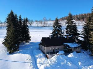 a house in the snow with trees and a field at Holiday Home Hoja 2 by Interhome in Vítkovice