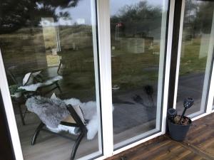 a screened in porch with a chair and a table at Holiday Home Lagho - 500m from the sea in NW Jutland by Interhome in Pandrup