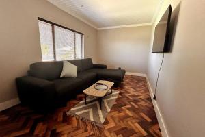 a living room with a black couch and a table at Embassy Apartment in Cape Town