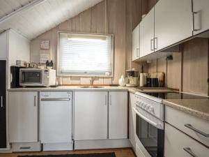 een keuken met witte kasten, een wastafel en een magnetron bij Holiday Home Anu - 400m from the sea in SE Jutland by Interhome in Aabenraa