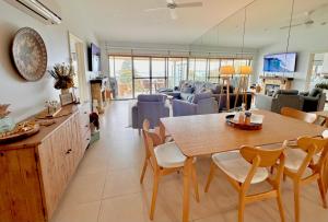 The Salty Seagull – ocean-view luxe! في Encounter Bay: غرفة طعام وغرفة معيشة مع طاولة وكراسي