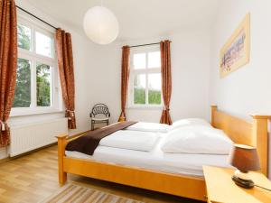 ein Schlafzimmer mit einem Bett und zwei Fenstern in der Unterkunft Apartment Wildrose by Interhome in Zempin