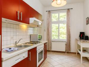 eine Küche mit roten Schränken, einem Waschbecken und einem Fenster in der Unterkunft Apartment Wildrose by Interhome in Zempin