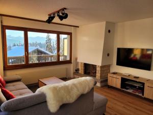 ein Wohnzimmer mit einem Sofa und einem TV in der Unterkunft Apartment Mandarin-5 by Interhome in Crans-Montana