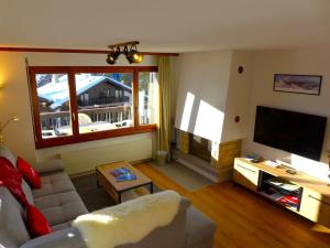 ein Wohnzimmer mit einem Sofa und einem Flachbild-TV in der Unterkunft Apartment Mandarin-5 by Interhome in Crans-Montana