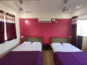 two beds in a room with purple sheets at Vasantam Beach Resort in Kashid