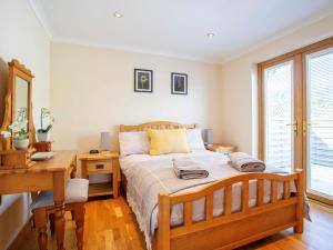 um quarto com uma cama de madeira, uma secretária e uma janela em 2 Bed in Ardross CA384 em Stittenham