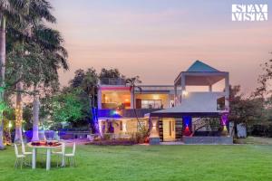 une maison avec une table et des chaises dans une cour dans l'établissement StayVista's Palm Perle Villa - Pet-Friendly Retreat with Terrace, Lawn & Pool Table, à Bhopal