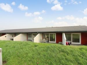 a red and white house on a grassy hill at Holiday Home Thorulf - 6km from the sea in Bornholm by Interhome in Åkirkeby