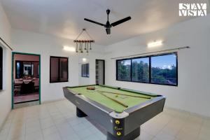 a pool table in a room with a ceiling fan at StayVista's Palm Perle Villa - Pet-Friendly Retreat with Terrace, Lawn & Pool Table in Bhopal
