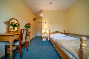a bedroom with a bed and a desk and a mirror at Hotel Gromada Zakopane in Zakopane