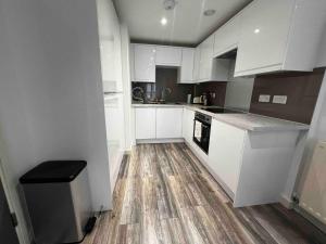 a kitchen with white cabinets and a wooden floor at Stylish 1-Bed Flat with Sofa-Bed in London in London