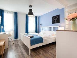 1 dormitorio con 1 cama blanca y paredes azules en Kostel Panzió, en Kesztölc