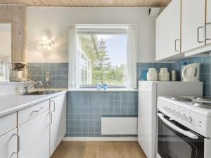 una cocina con azulejos azules y una ventana en Holiday Home Gisa - 500m from the sea in NW Jutland by Interhome en Fjerritslev