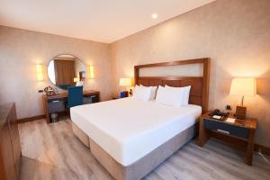 a bedroom with a large white bed and a desk at Dedeman Konya Hotel Convention Center in Konya