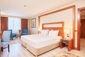 a bedroom with a large white bed and a blue chair at Dedeman Konya Hotel Convention Center in Konya