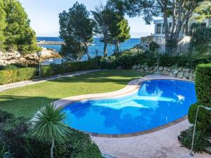 a swimming pool in a yard with the ocean in the background at Apartment Cala Llobeta by Interhome in L'Ametlla de Mar