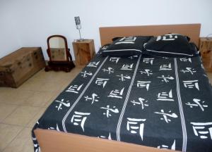una cama con un edredón blanco y negro con letras de chino. en chambres d'hôtes saint gilles les bains en Saint-Gilles-les-Bains