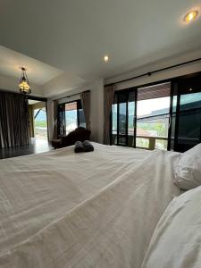 a large white bed in a room with large windows at Supreme Siam Resort in Koh Samui 