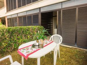 a white table with two chairs and a bottle of wine at Apartment Magnolia-16 by Interhome in Marina di Bibbona