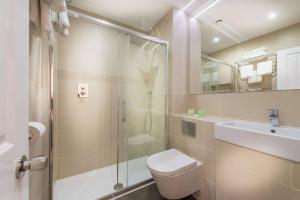 Un baño con ducha, inodoro y lavabo. en Athena Hotel, en Londres