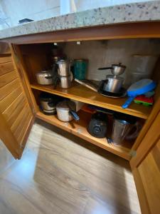a kitchen cabinet with pots and pans on a shelf at Apartamento Charme Guará in Guaramiranga