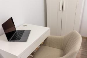 - un ordinateur portable sur un bureau blanc à côté d'une chaise dans l'établissement Minerva Studio Craiova, à Craiova