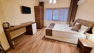 Un dormitorio con una cama, un escritorio y un televisor. en La Pearl Konaklama, en Estambul