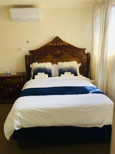 ein großes Bett mit einem Kopfteil aus Holz im Schlafzimmer in der Unterkunft Rose-Lee Cottage in Durban
