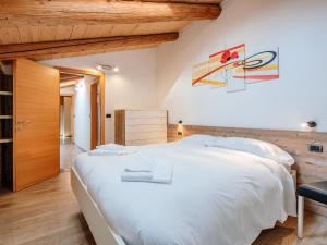 Cette chambre dispose d'un grand lit blanc et de plafonds en bois. dans l'établissement Apartment Casa Marta by Interhome, à Canazei