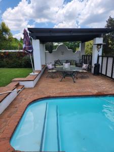 a pool with a patio with a table and chairs at Aleia Cottage in Pretoria