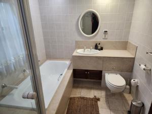 a bathroom with a tub and a toilet and a sink at Aleia Cottage in Pretoria