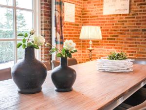 two black vases sitting on a wooden table with flowers at Holiday Home De Bron by Interhome in Losser