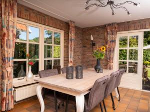 a dining room with a table and chairs and windows at Holiday Home De Bron by Interhome in Losser