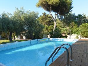 a blue swimming pool with a metal rail next to trees at Holiday Home Fanusa by Interhome in Siracusa