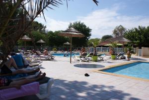 a group of people sitting around a swimming pool at Camping L' Arlesienne in Arles
