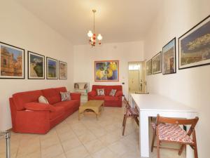 Una sala de estar con un sofá rojo y una mesa. en Villa Giardino delle Meraviglie by Interhome, en Floridia
