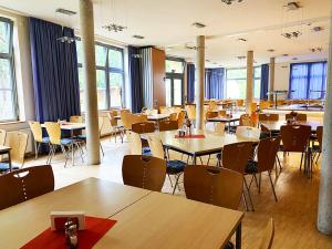 a dining room with tables and chairs and windows at A&S Ferienzentrum Schwerin in Schwerin