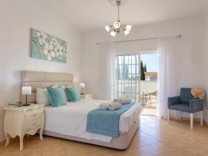 um quarto com uma cama branca e uma cadeira azul em Villa Jardin d'Eden by Interhome em Albufeira