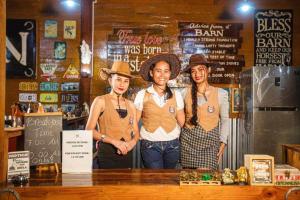 three people wearing cowboy hats standing behind a counter at Barn Hostel in Panglao Island