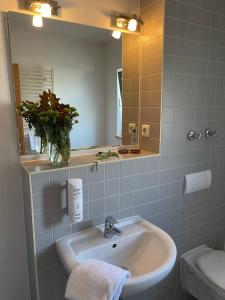 a bathroom with a sink and a vase of flowers at A&S Ferienzentrum Schwerin in Schwerin +13 photos